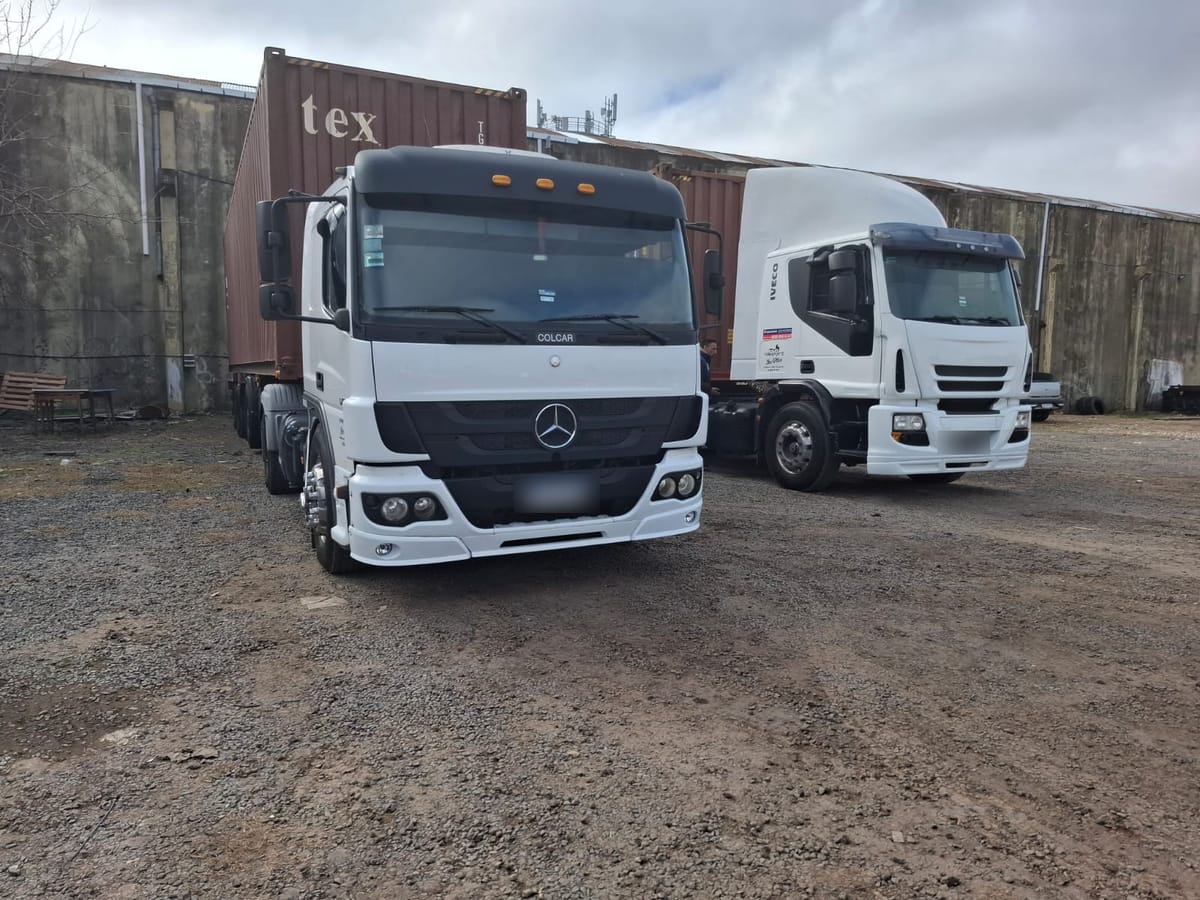 Camiones Mercedes-Benz Atego e Iveco blancos estacionados frente a contenedores