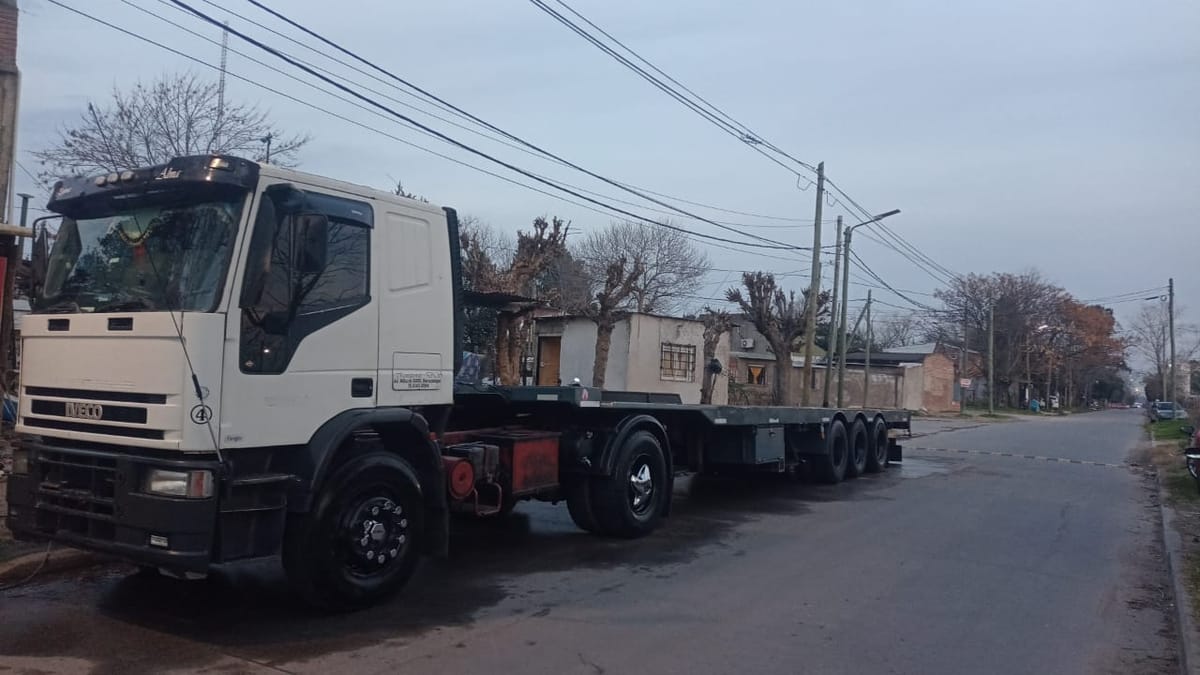 Camión Iveco blanco con semirremolque playo estacionado en una calle